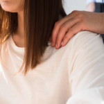 Männliche Hand auf einer weiblichen Schulter