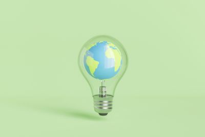 Globus in Glühbirne vor grünem Hintergrund