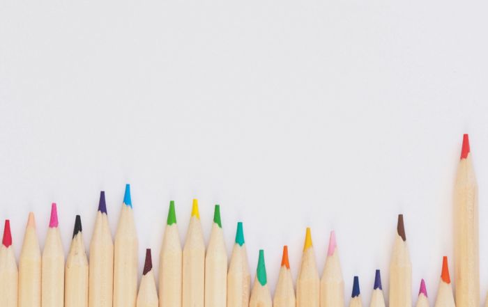 Aneinander gereihte Buntstifte vor weißem Hintergrund